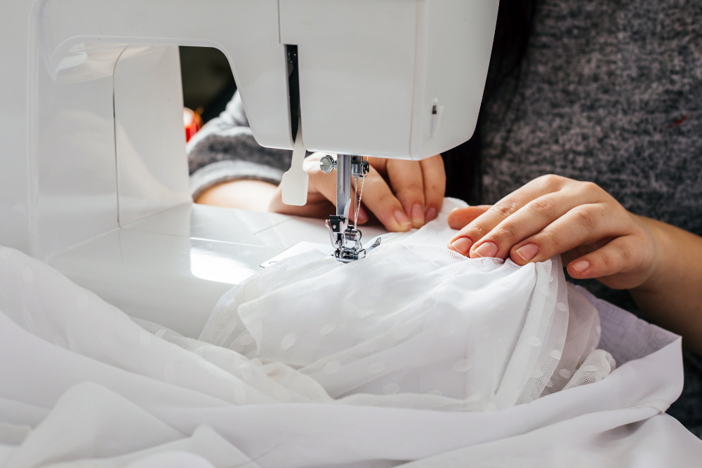 A woman sewing on white fabric with a sewing machine